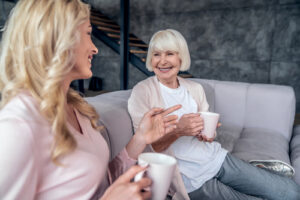 Two smiling women drinking coffee together