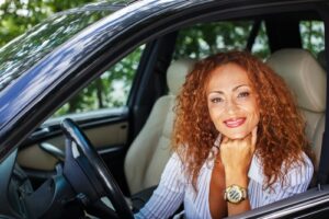 A smiling woman posing in the driver's seat of a car