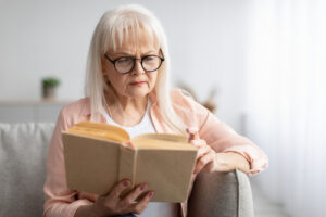 older woman trying to read book